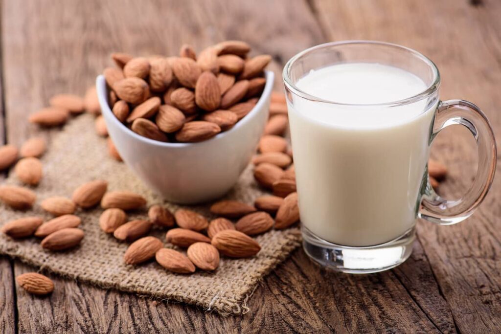 a glass of almond milk and almonds on the table